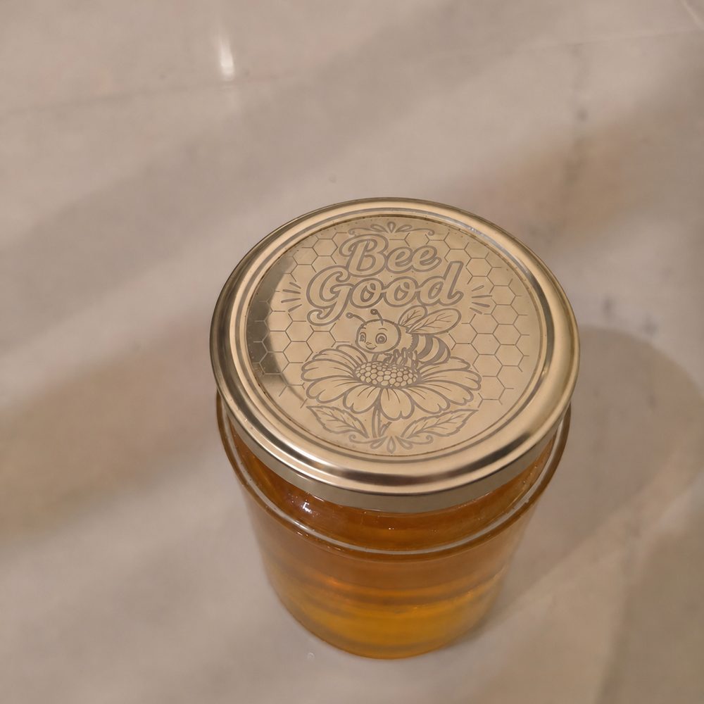 Honey jar with a bee and honeycomb design engraved into its gold lid