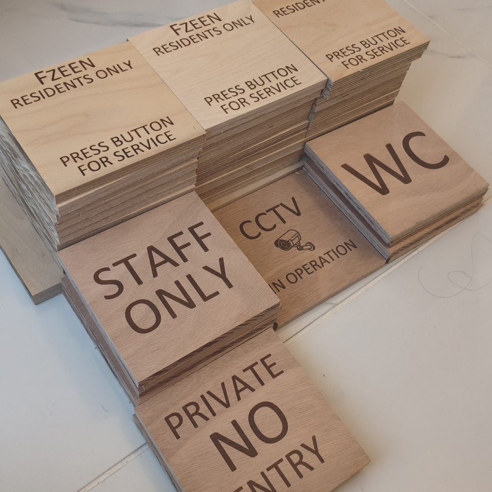 Stacks of engraved plywood signs for a hotel: residents only, staff only, CCTV, WC and no entry